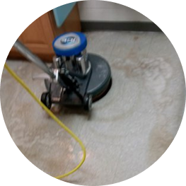 Industrial floor-scrubbing machine cleaning a tile floor inside a facility